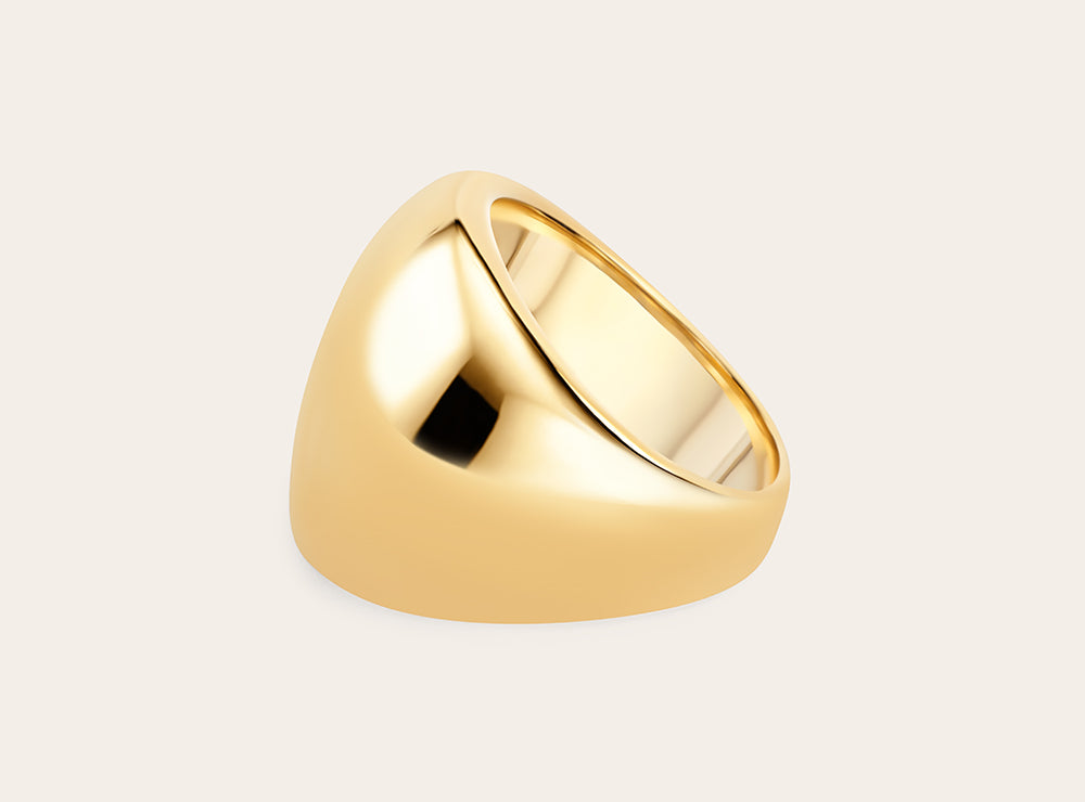 Side view of the golden signature ring on a flat white background. 