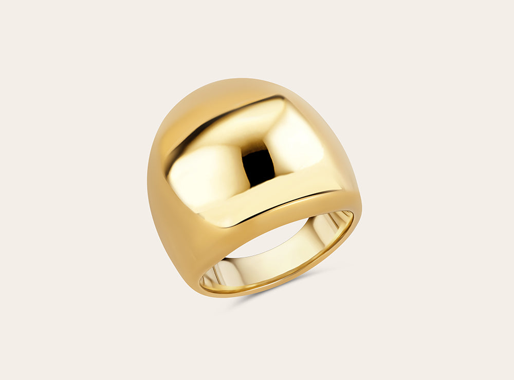 Product photo of the golden statement ring on a light background. Perspective from above. 