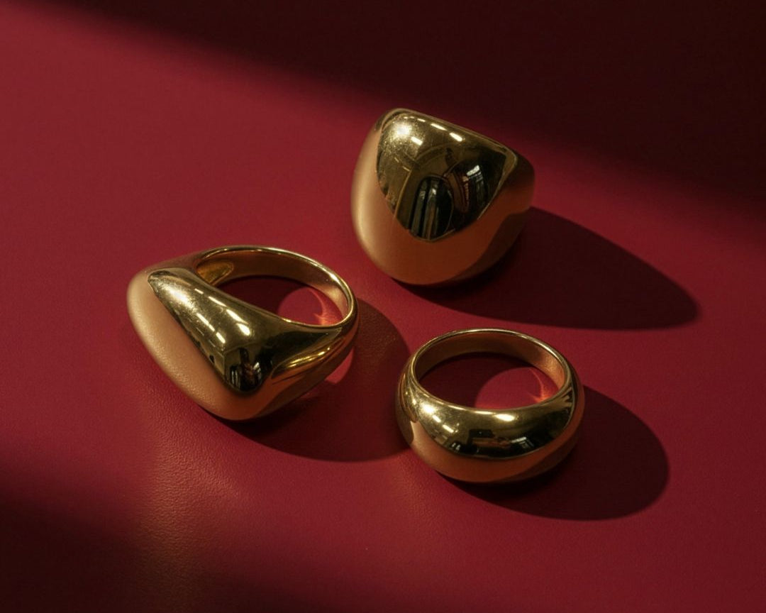 Product photo of the three golden rings on a flat red background. 