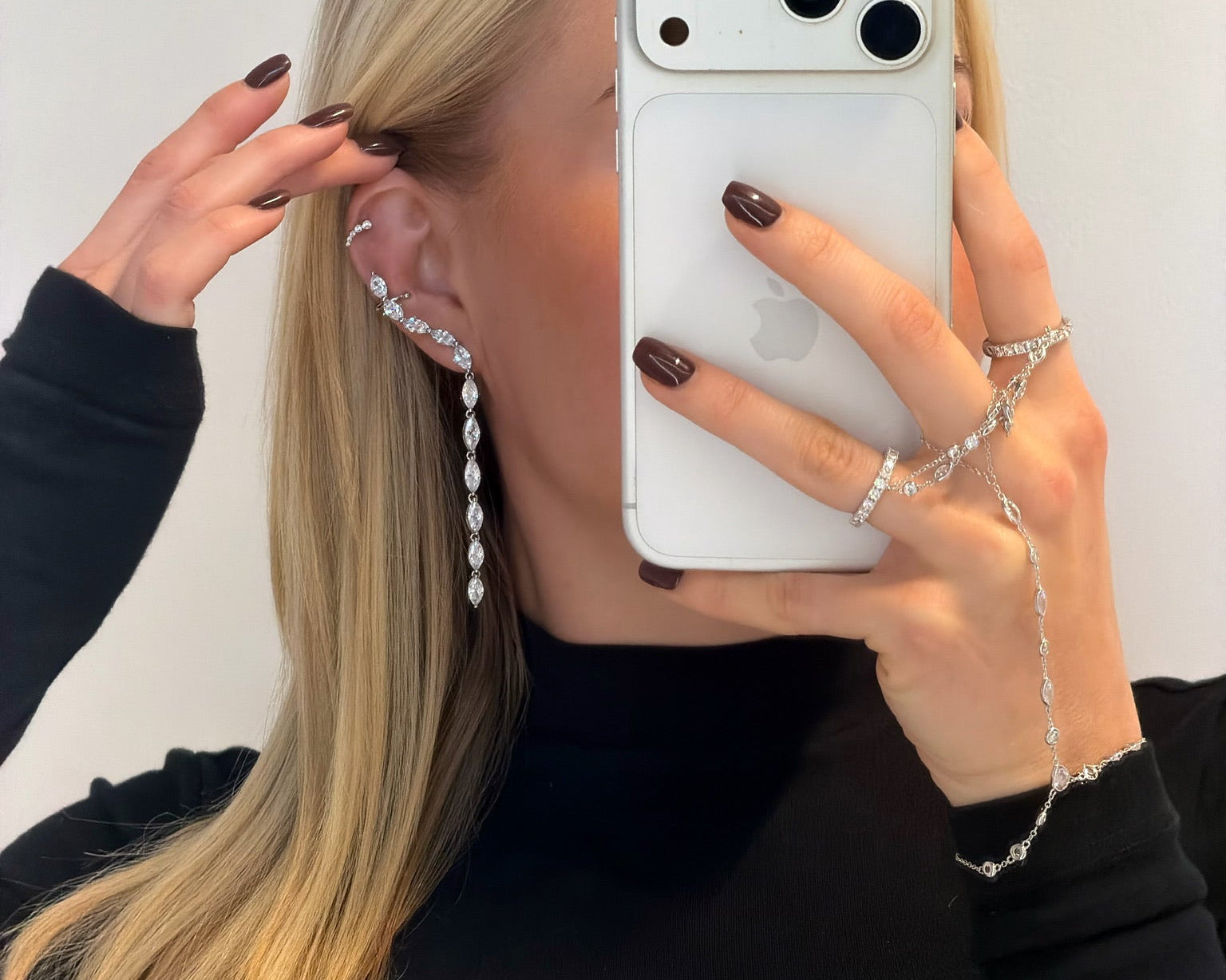 Woman wearing the silver hand chain with a black outfit and matching earrings and ring
