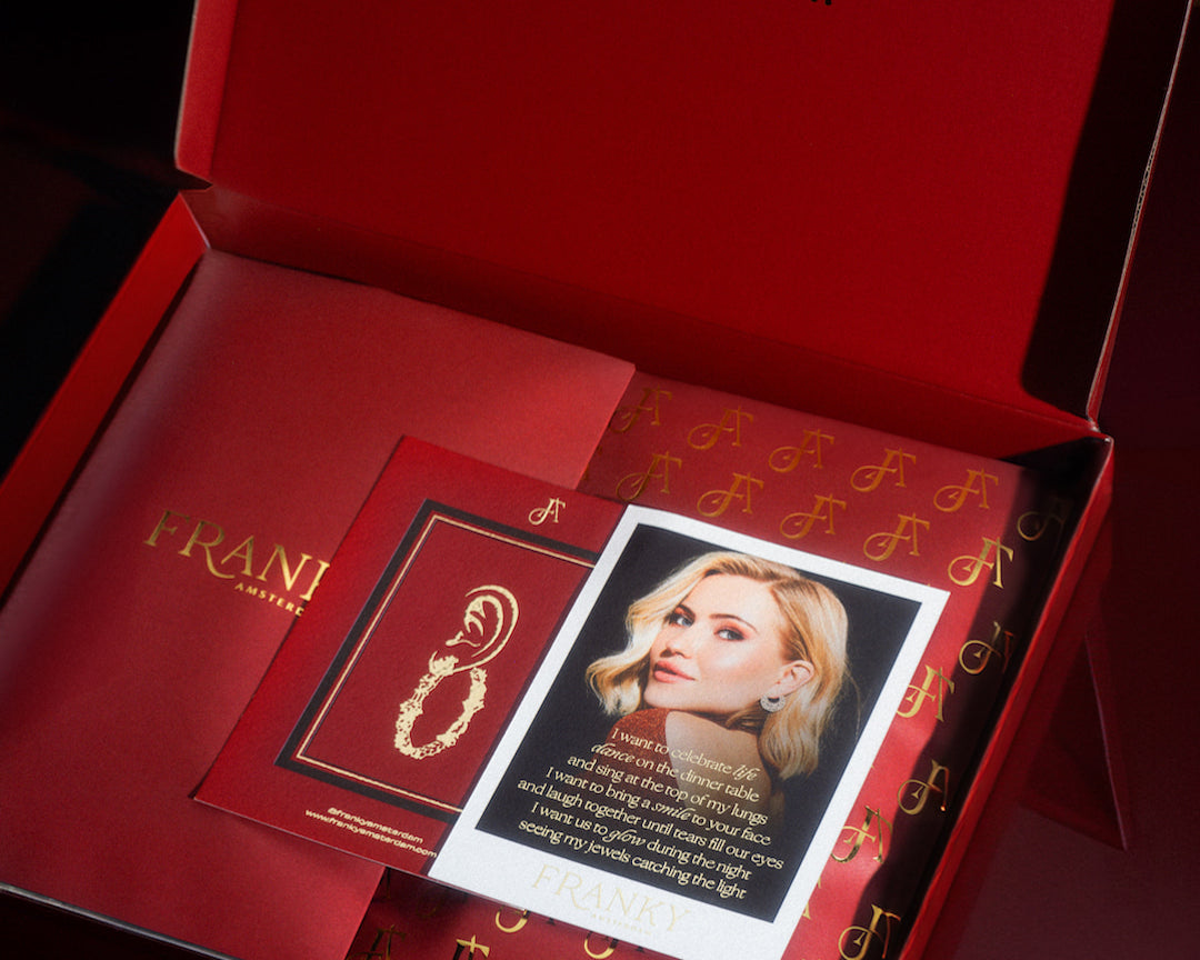 A photo of the red package box. In the box is a red pouch and a card of Franka. 