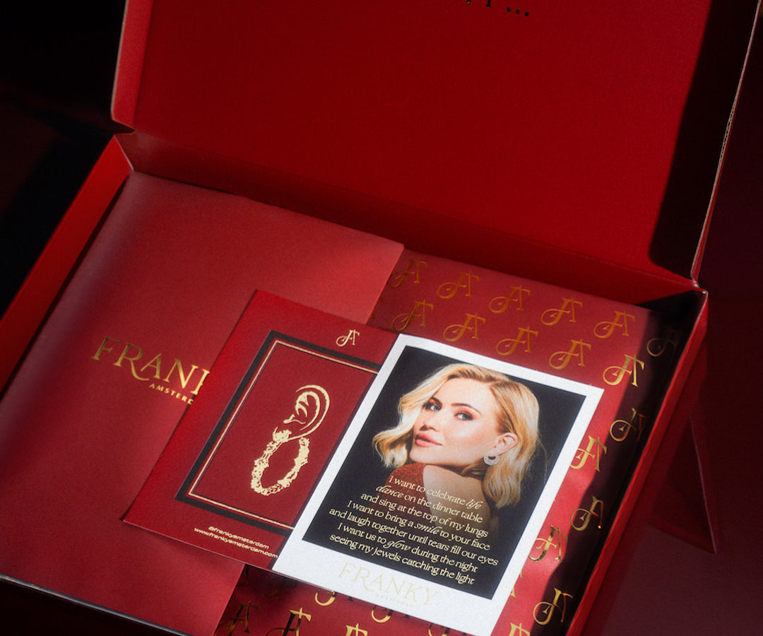 Photo of the packaging. A red box, a red pouch and card of Franka. 