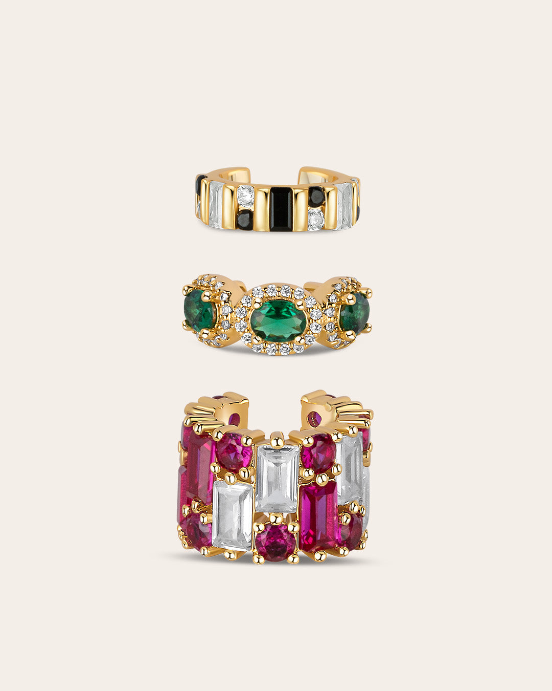 Product photo of the ear cuff set of three with a light background. One is black and white, one with green stones and one with pink stones.