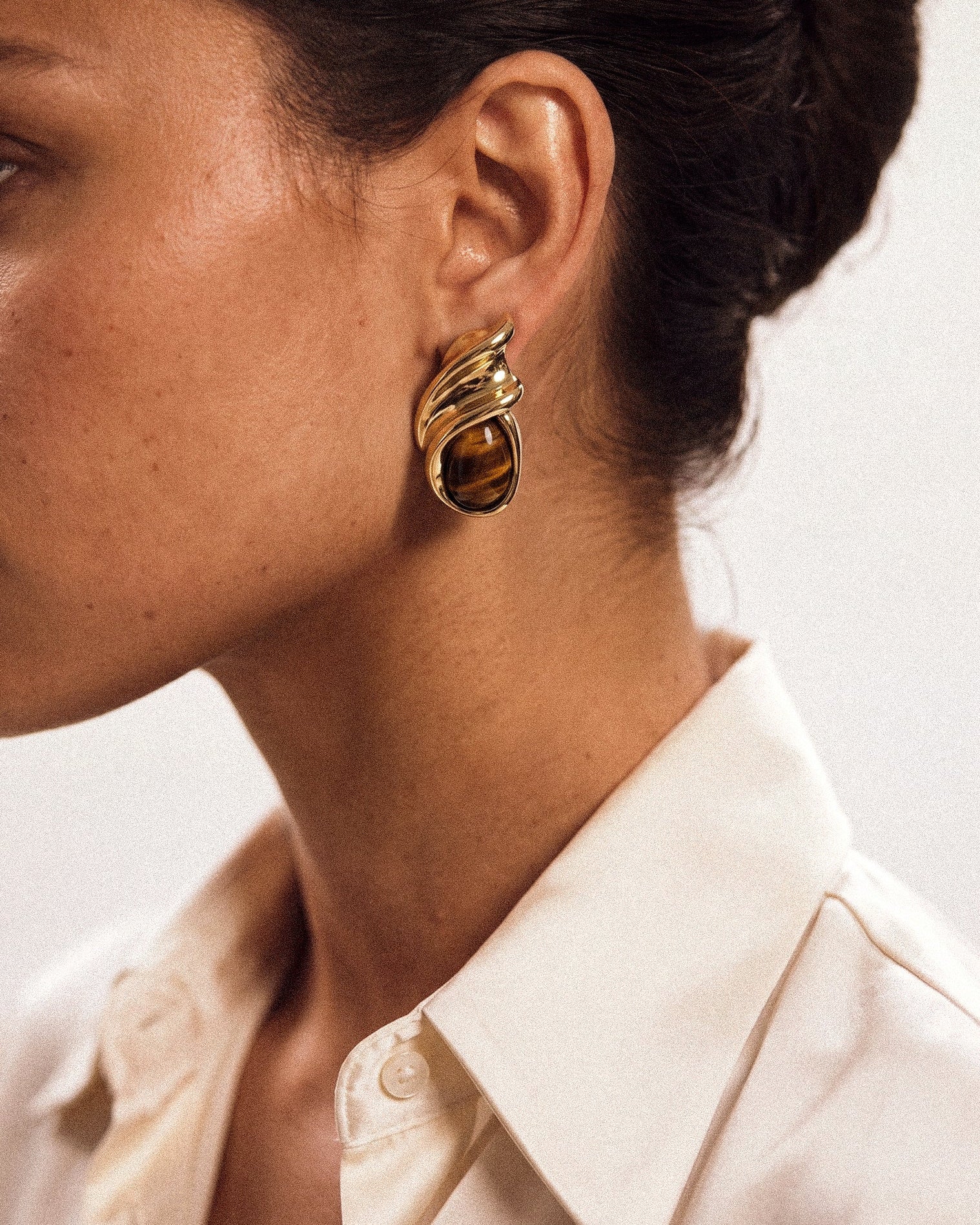Model wearing gold plated earrings with brown stones