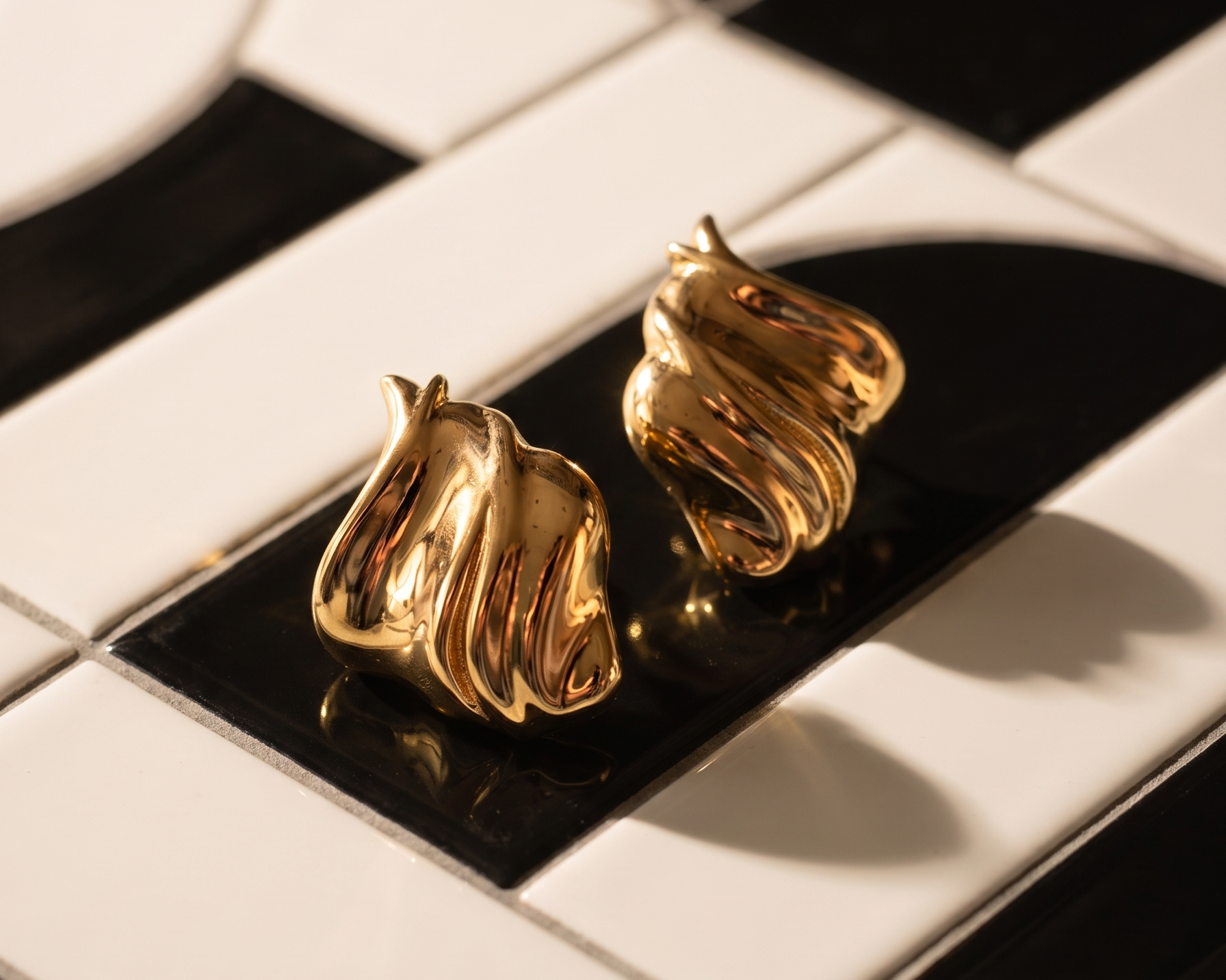 Gold plated earrings on a black and white surface