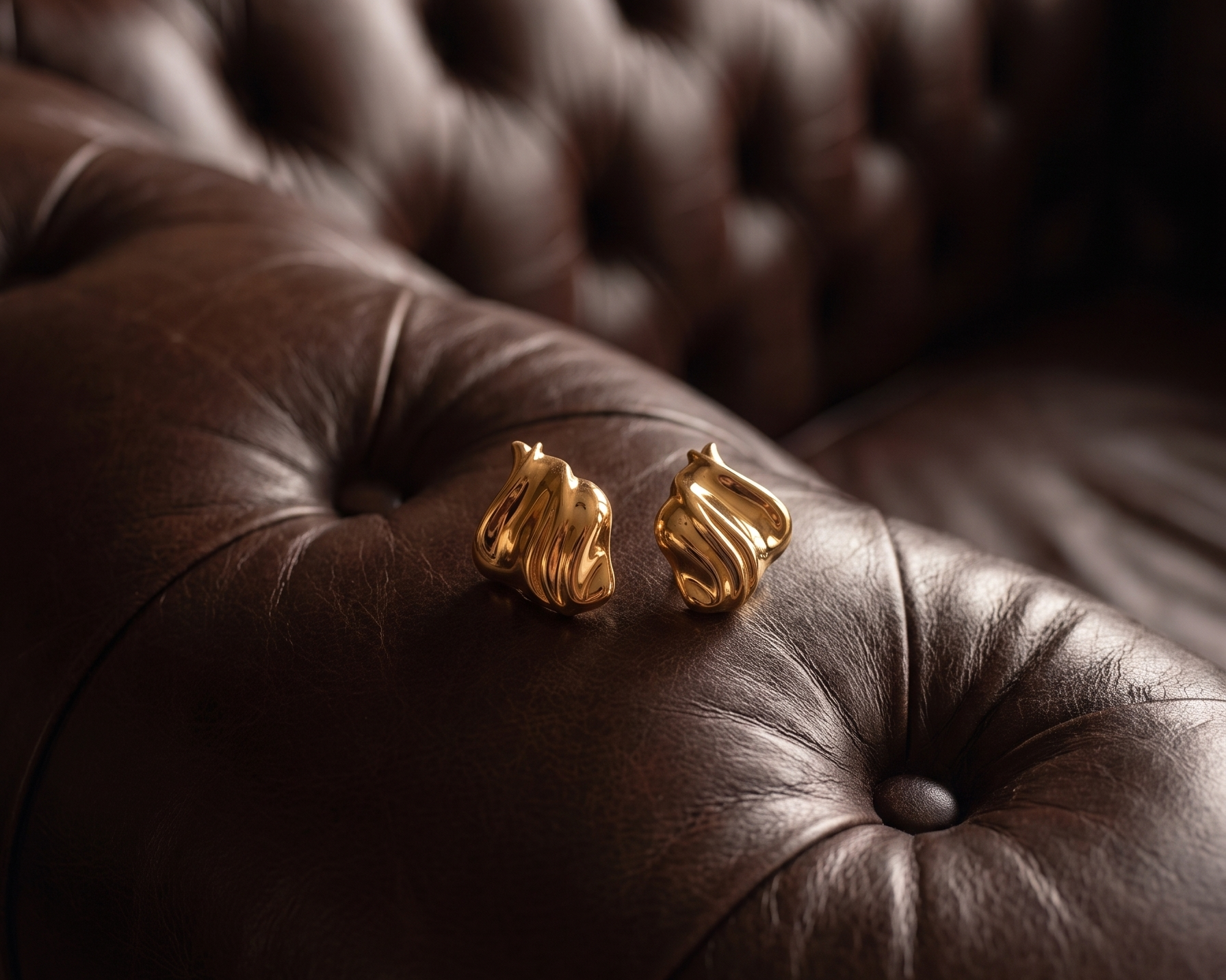 Gold plated statement earrings on a leather chair